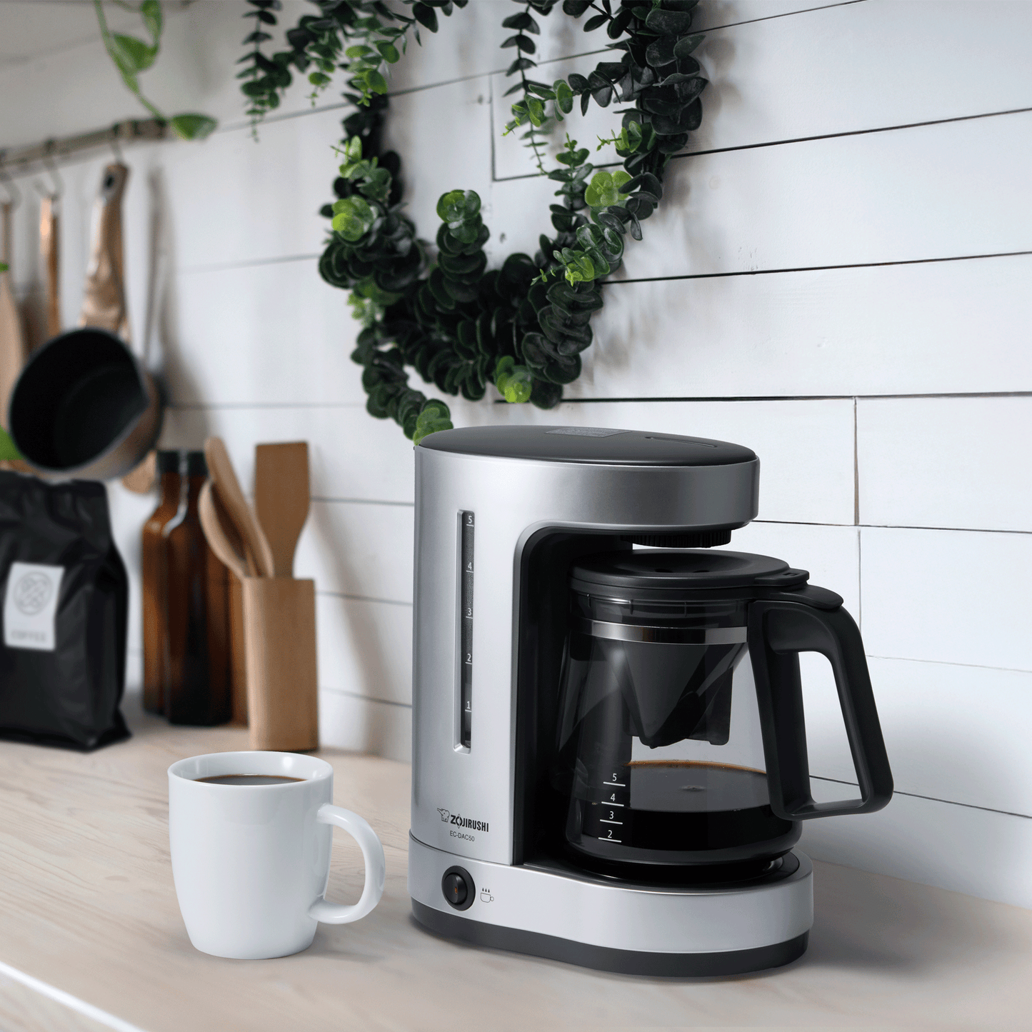 EC-DAC50 Coffee Maker on a kitchen countertop. A cup of hot coffee is placed next to the product.