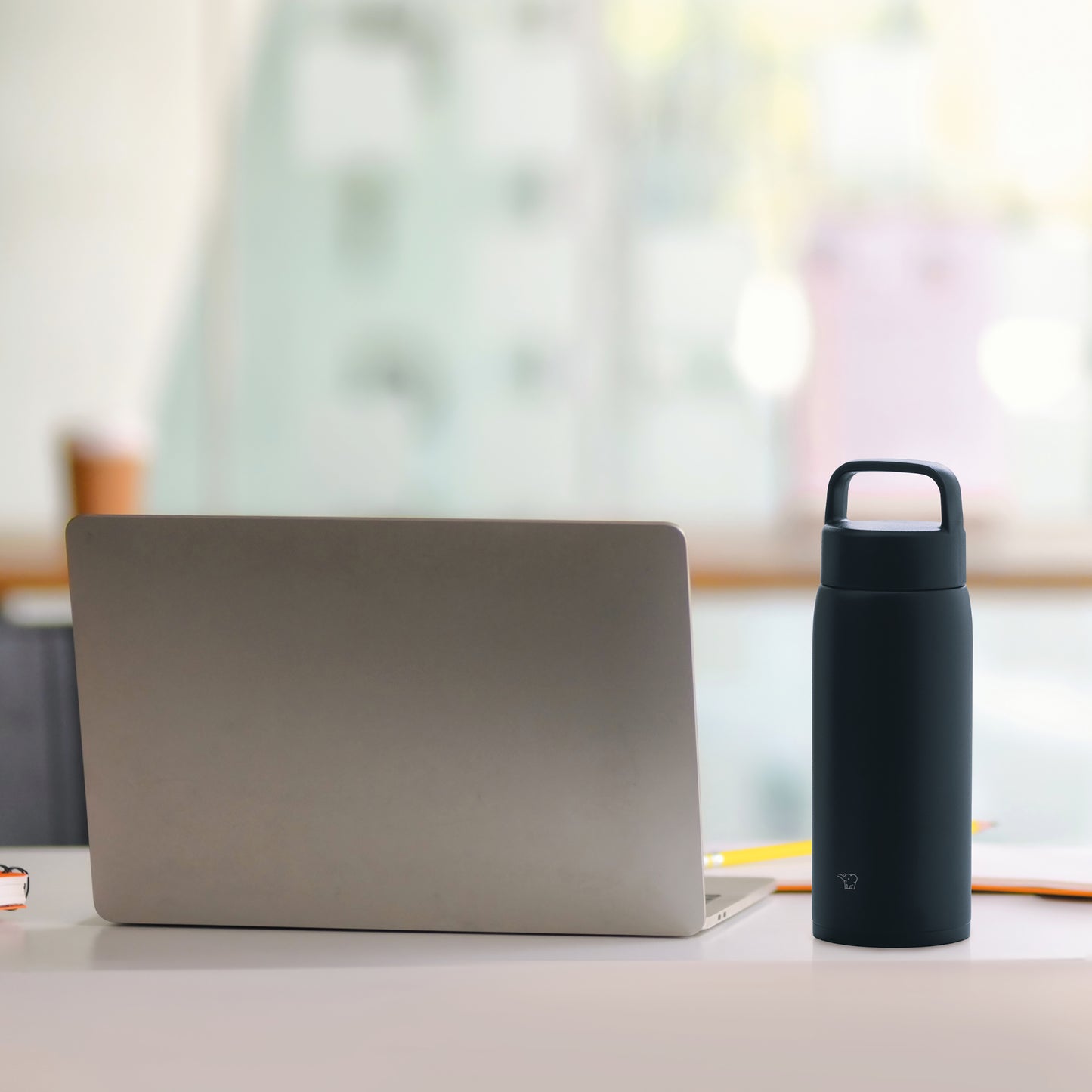 Bottle on the desk next to a laptop