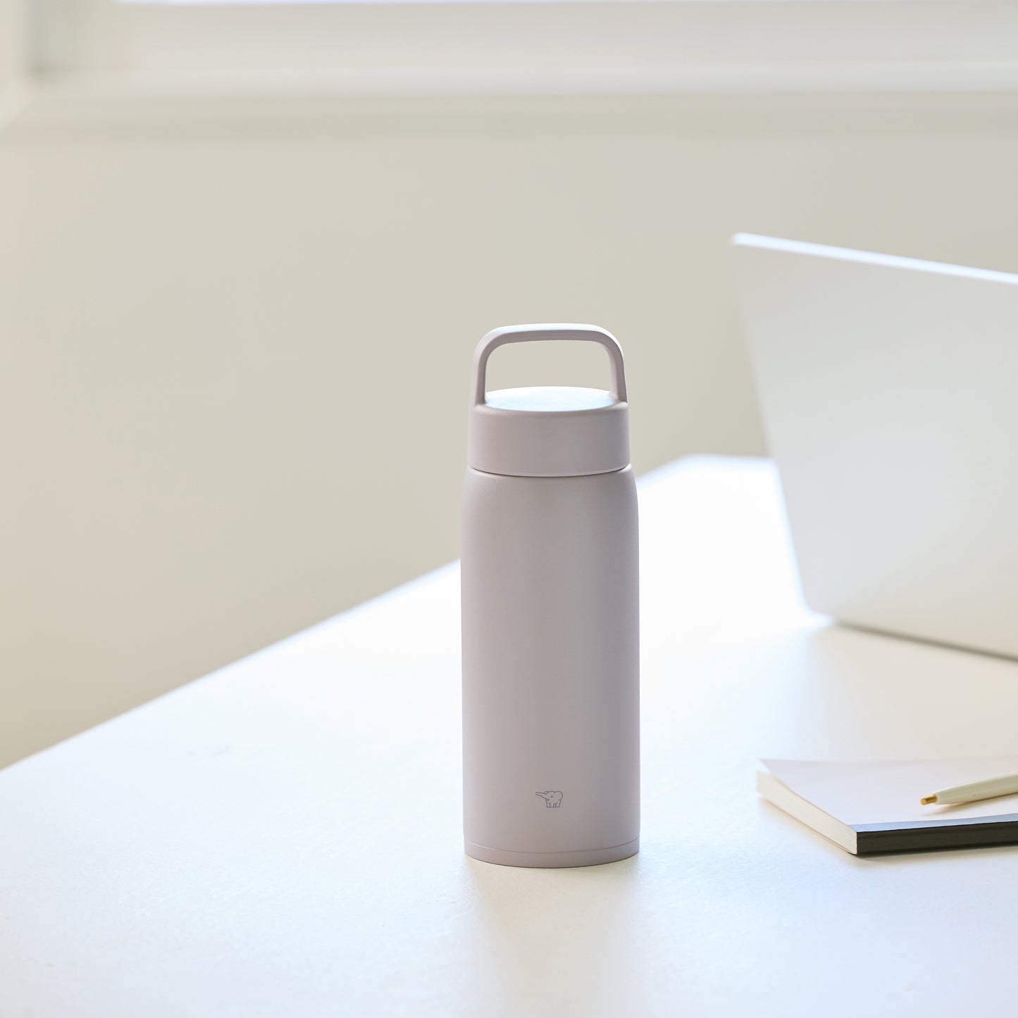Bottle on a desk next to a laptop