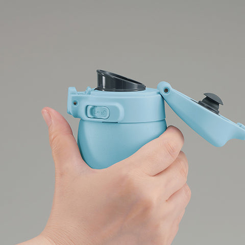 Hand holding a blue thermos with a gray background
