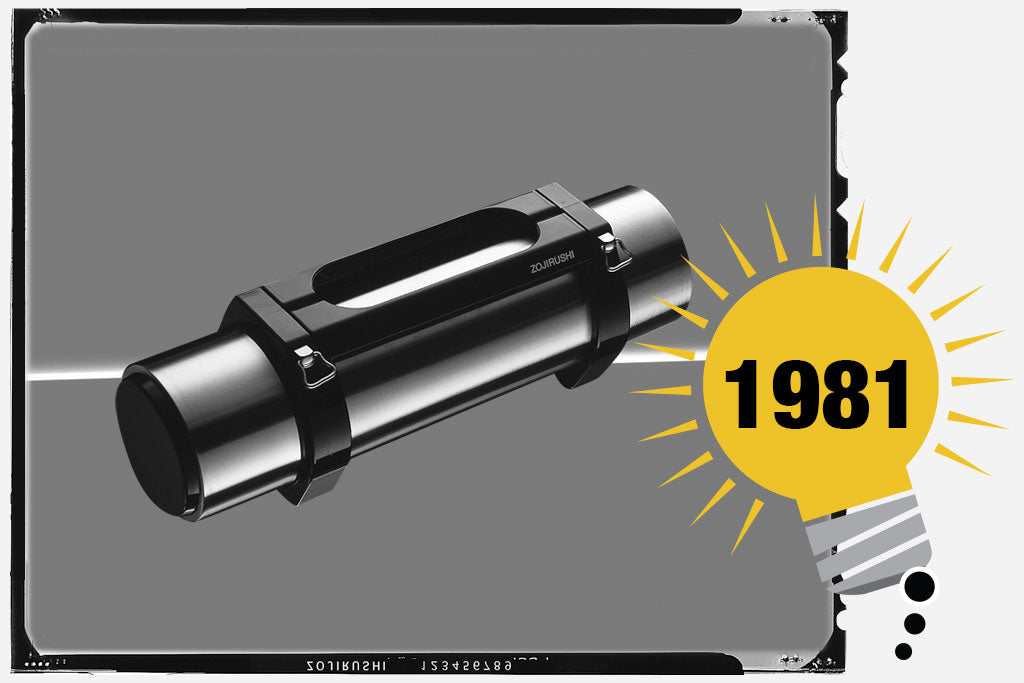 Black and white photo of Zojirushi’s first insulated drink bottle the Tuff Boy. The unit has a cylinder shape with a stainless exterior and black handle. Photo is labeled with the year 1981.