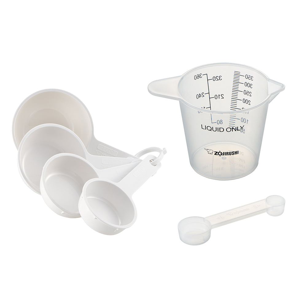 Set of white nested measuring cups, clear liquid measuring cup and spoon on a white background