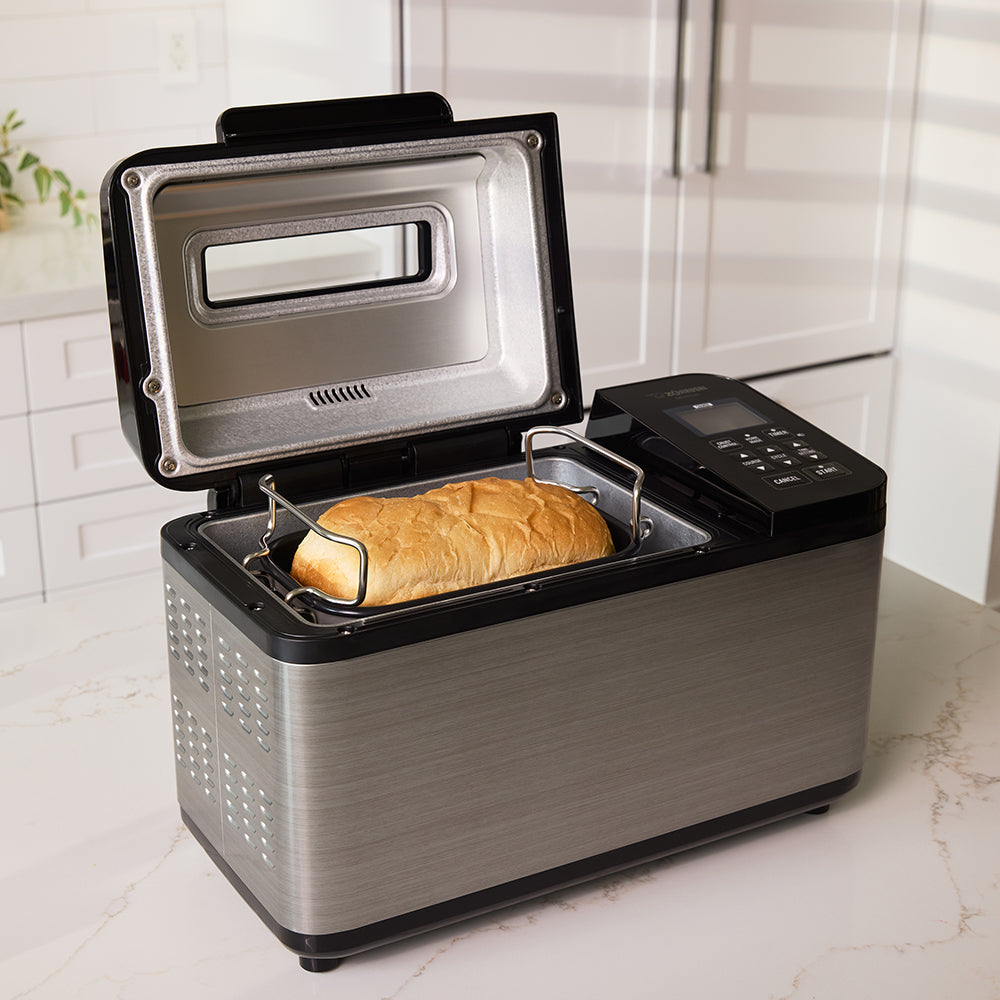 Bread maker with a loaf of bread inside on a kitchen counter.