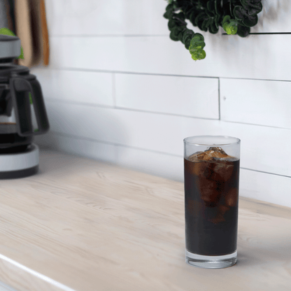 A tall cup of iced coffee is on a kitchen countertop, with the EC-DAC50 Coffee Maker in the background.
