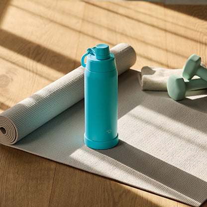 Blue water bottle on a yoga mat with a towel and weights in the background