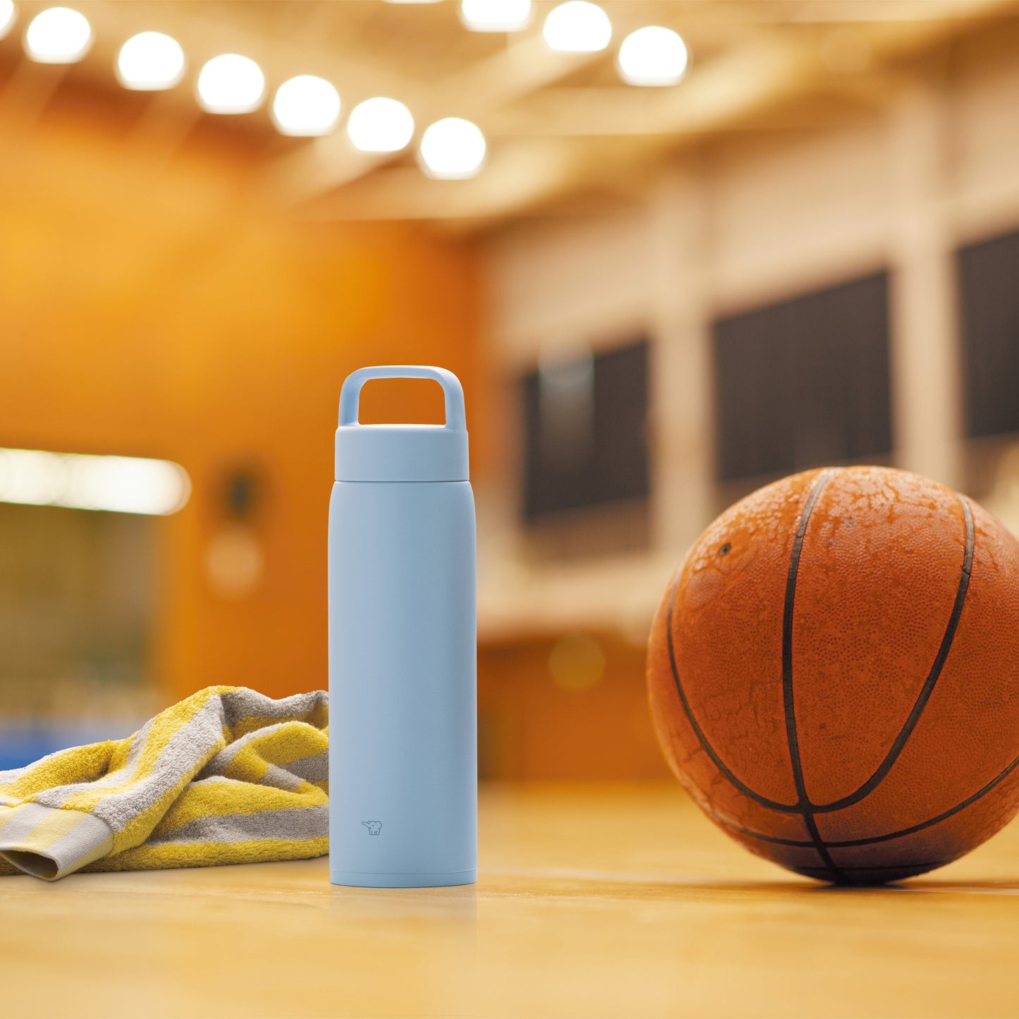 Bottle in the gym with a basket ball and towel