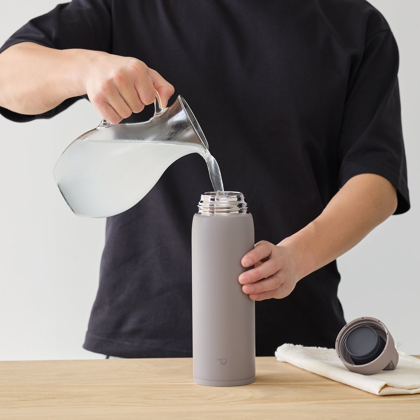 Pouring water from a pitcher into the bottle