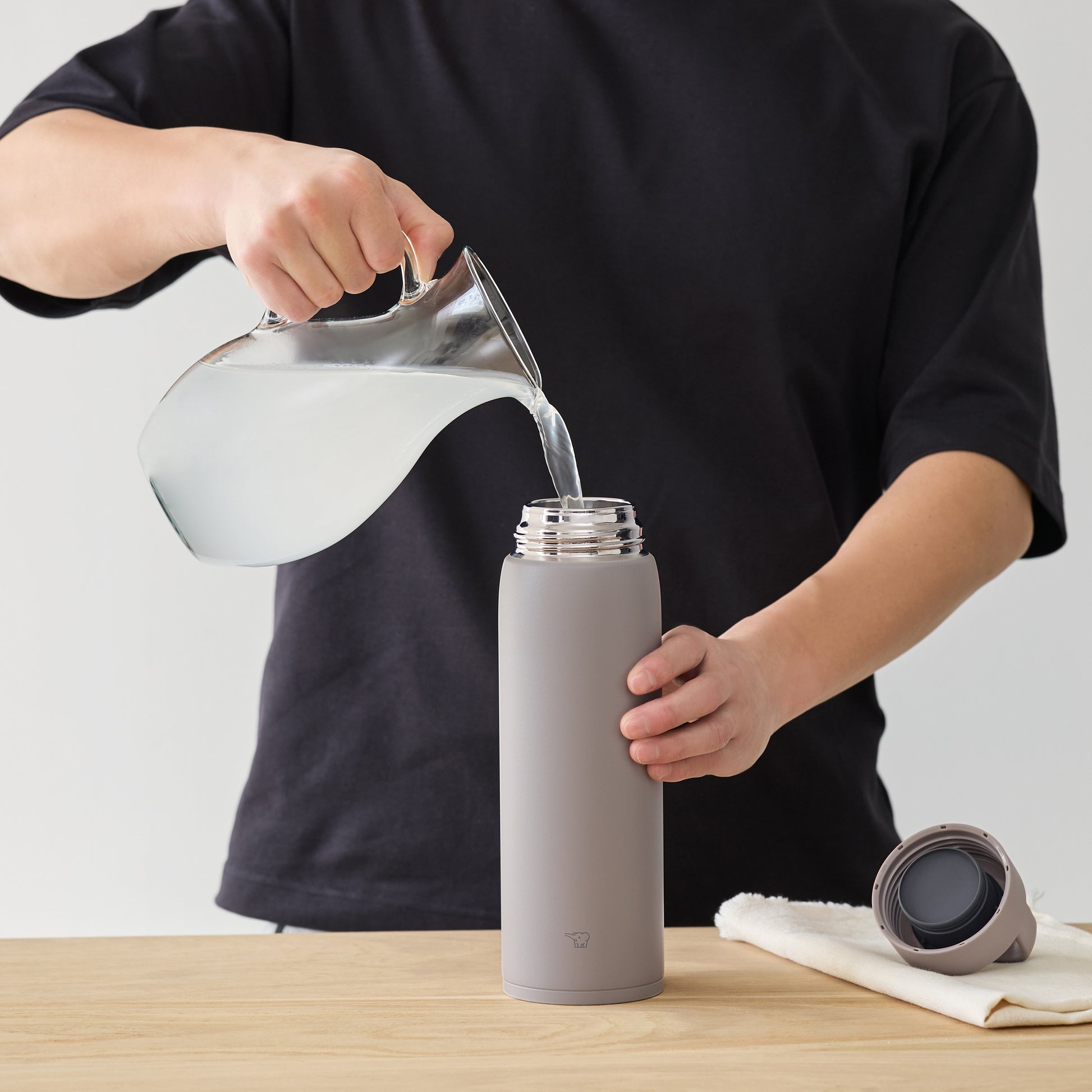 Pouring water from a pitcher into the bottle