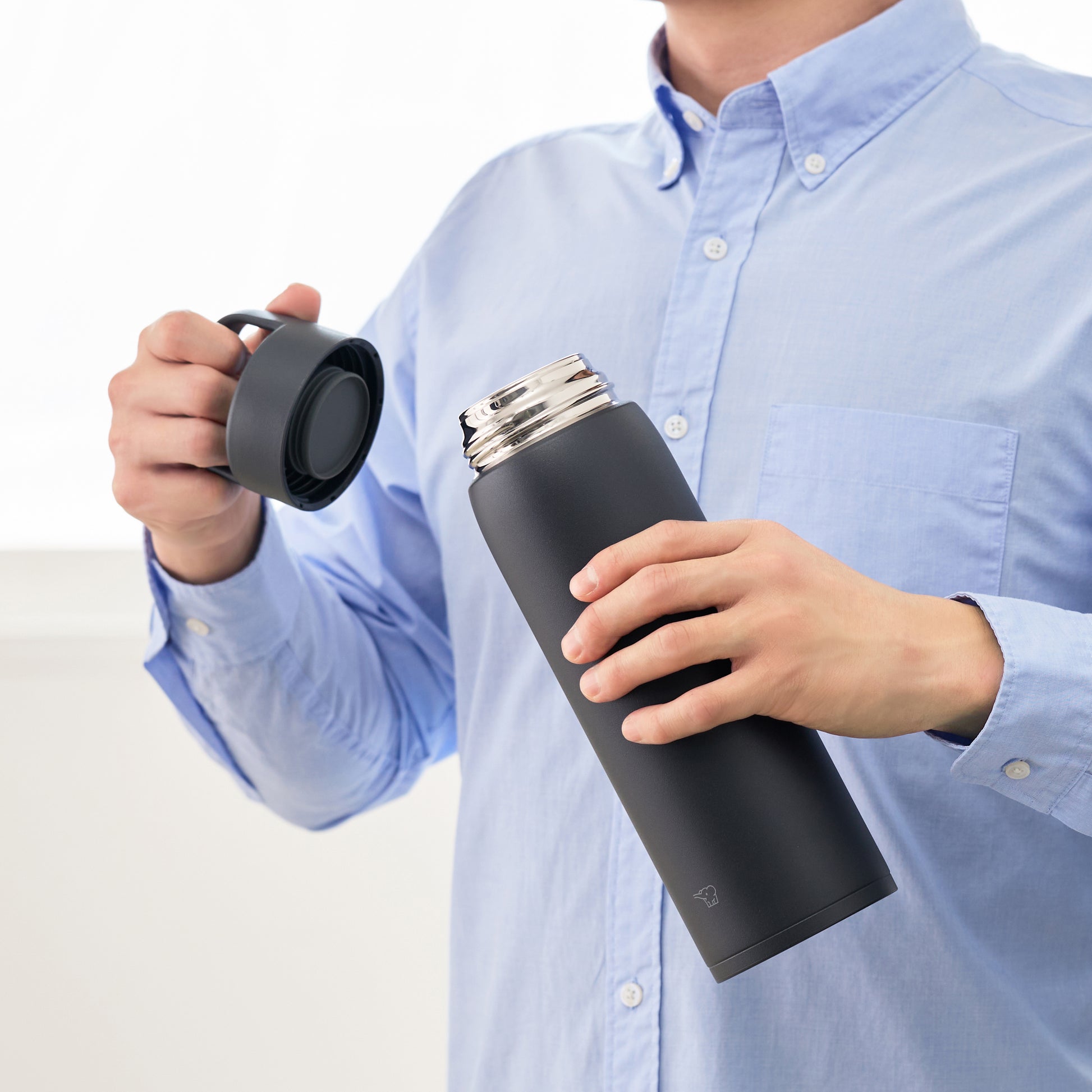 Holding the bottle in one hand and the lid in the other