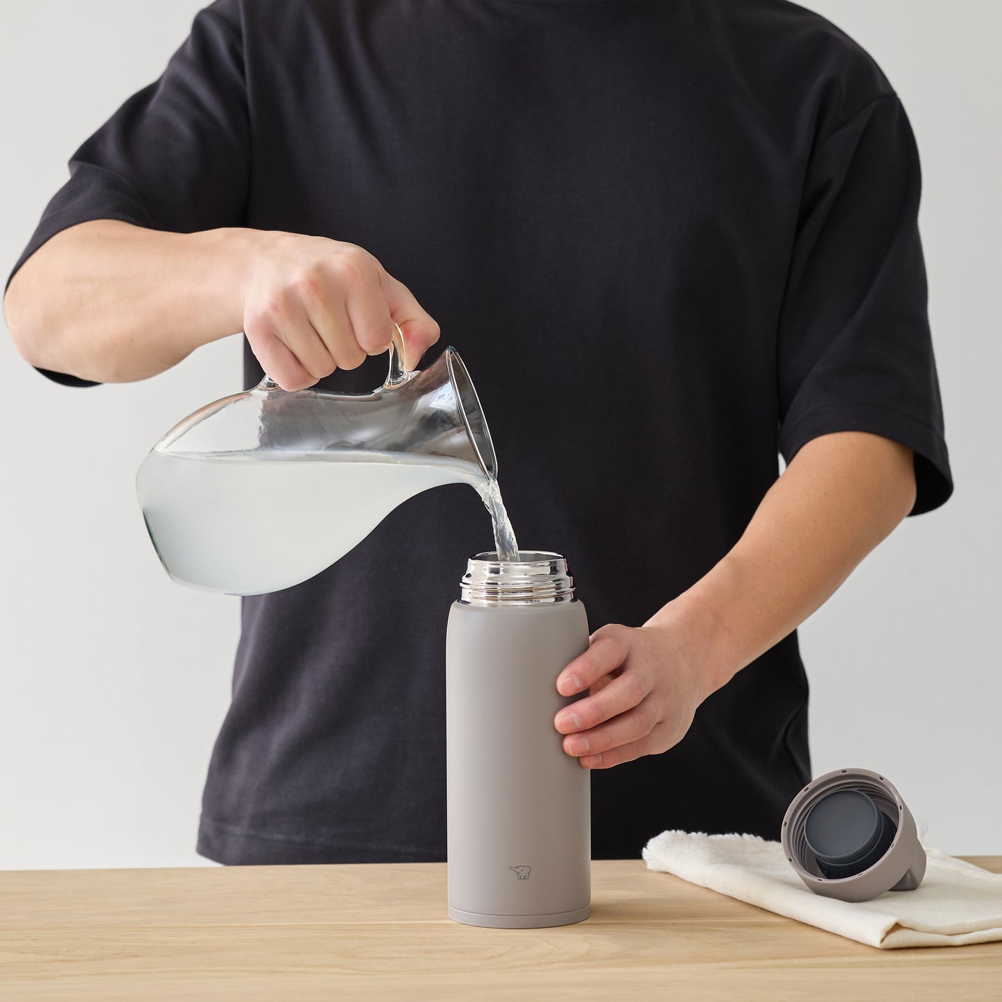 Pouring water from a pitcher into the bottle