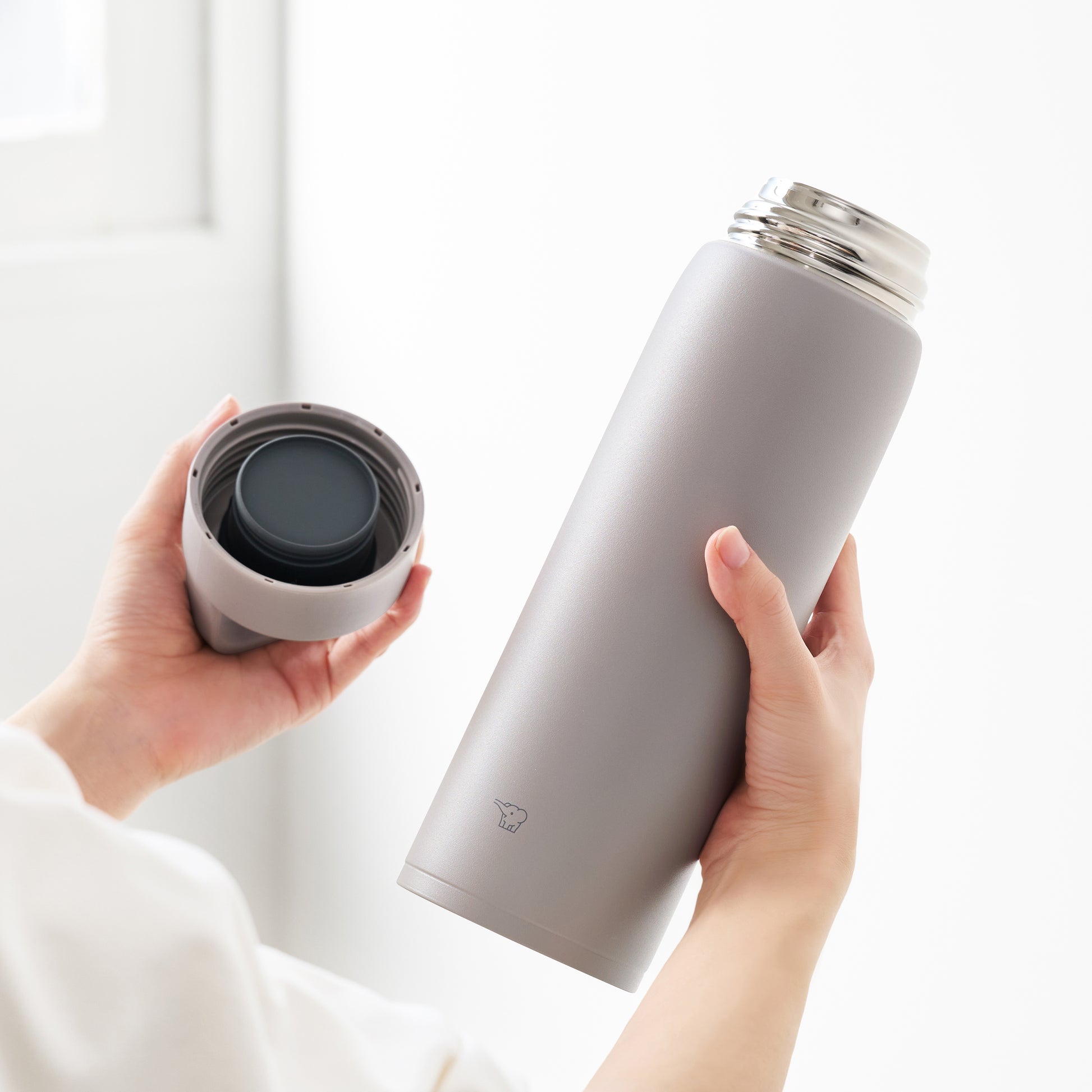 Hand holding bottle in one hand and the lid in the other