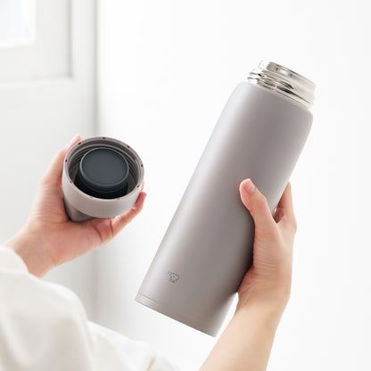 Hand holding bottle in one hand and the lid in the other